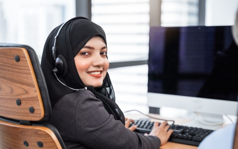 a person wearing a hijab is sitting at a desk in front of a computer