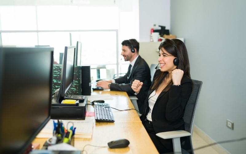 two people in an office with computers and headsets